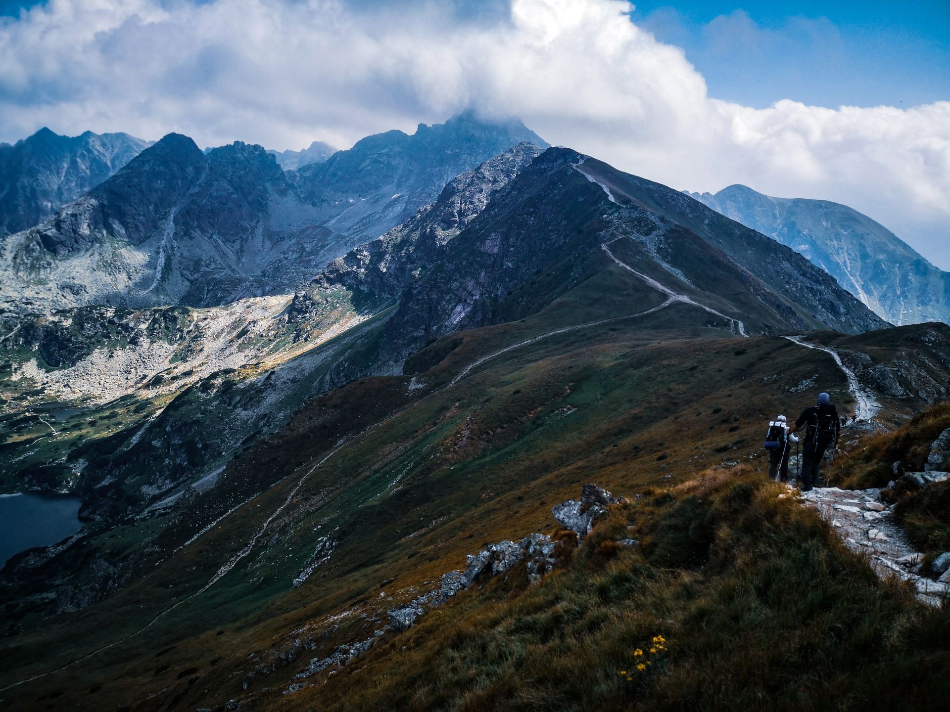 Weite Berglandschaft mit Wanderweg und Wanderern